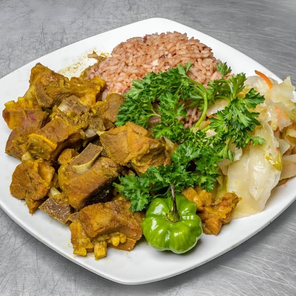 Curried goat with rice and peas, steamed cabbage, and a green scotch bonnet pepper.